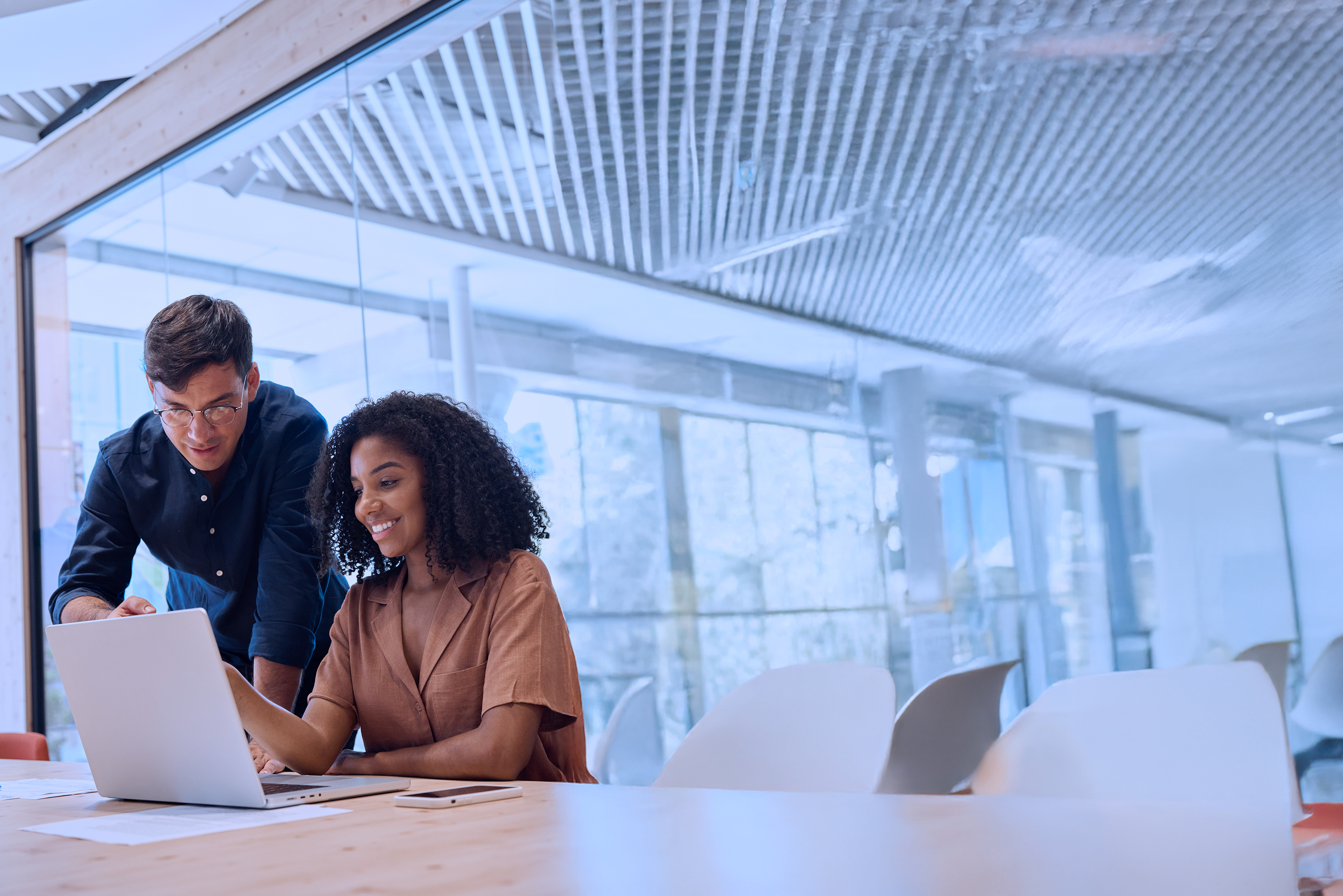 Two young busy diverse coworkers, professional business man and business woman executive company team or employees working together standing in office discussing project documents